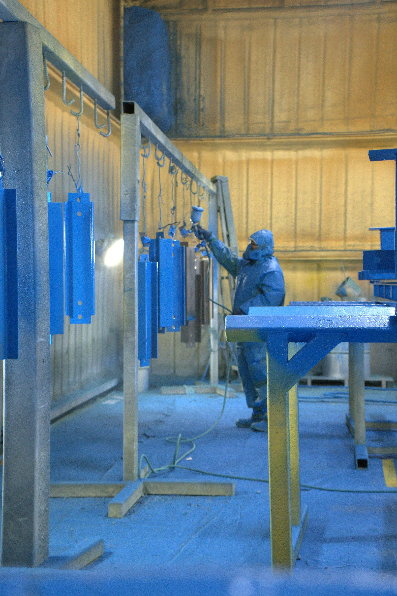 Painter spraying fabricated parts at the Hawk Fabrication shop